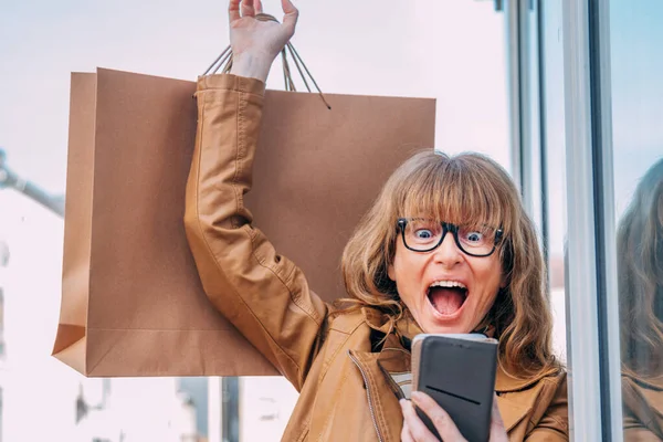 Opgewonden Vrouw Met Boodschappentassen Mobiele Telefoon Straat — Stockfoto