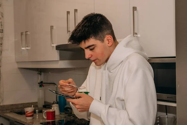 Έφηβος Άνδρας Στην Κουζίνα Τρώει Πρωινό Smartphone — Φωτογραφία Αρχείου