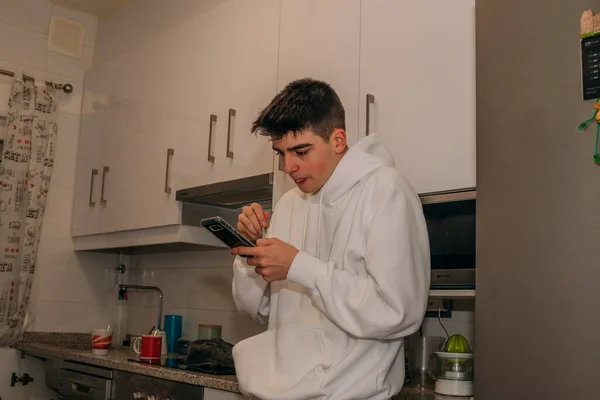 Νεαρός Έφηβος Που Χρησιμοποιεί Κινητό Τηλέφωνο Στην Κουζίνα Στο Σπίτι — Φωτογραφία Αρχείου