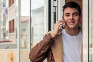 Genç adam kapıda cep telefonuyla konuşuyor.