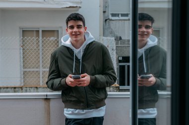 Terasta cep telefonu olan genç bir adam.