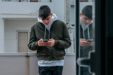 Terasta cep telefonu olan genç bir adam.