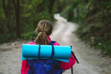Sırt çantalı bir kadın yolda yürüyor.