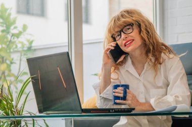 Cep telefonu ve bilgisayarı olan bir kadın.