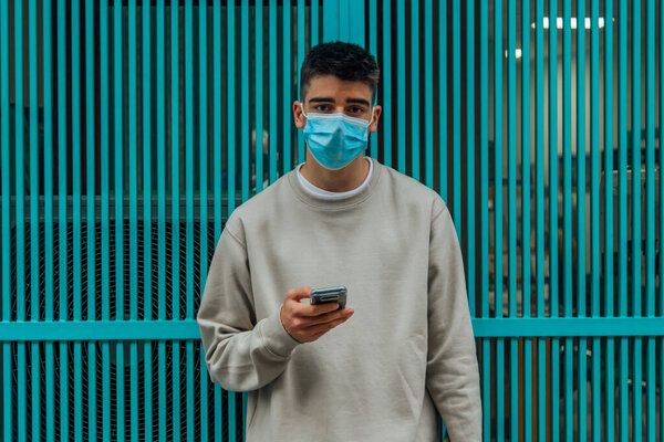 Male adolescent with mask and mobile phone