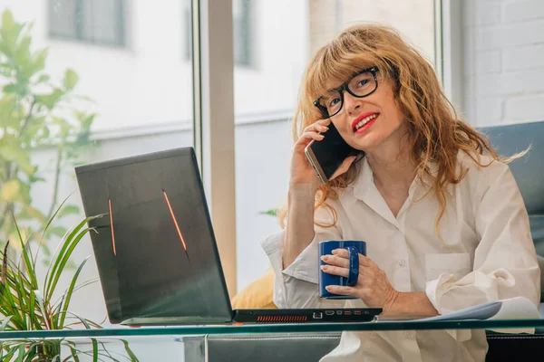 Cep telefonu ve bilgisayarı olan bir kadın.