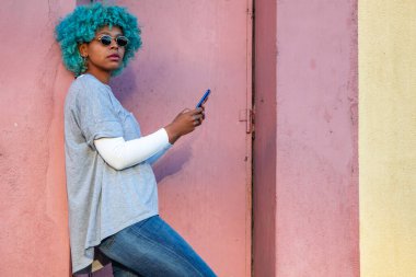 Siyah saçlı ve cep telefonlu Afro-Amerikalı kız.