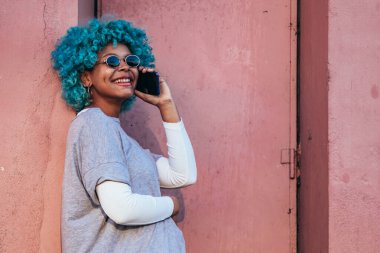 Siyah saçlı ve cep telefonlu Afro-Amerikalı kız.