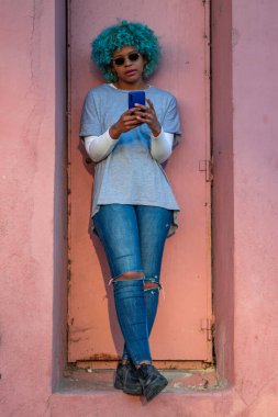 Siyah saçlı ve cep telefonlu Afro-Amerikalı kız.