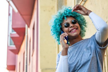 Afro-Amerikalı kız sokakta cep telefonuyla konuşuyor.