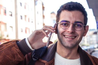 Gözlüklü ve cep telefonlu genç adamın portresi