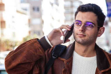 Şehir caddesinde akıllı telefon kullanan genç adamın portresi