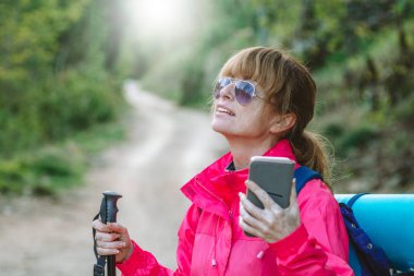 Cep telefonu ve seyahat çantası olan bir kadın.