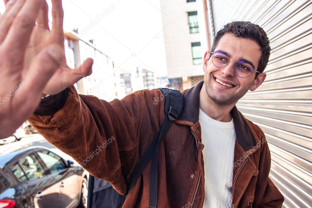 smiling young man waving in the street