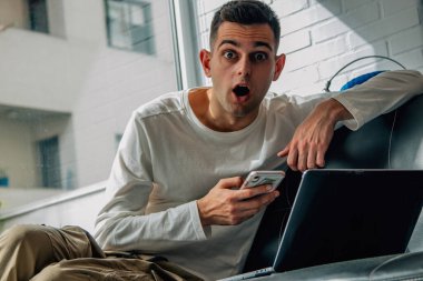 Şaşkınlık ifadesi olan ya da cep telefonu ve bilgisayarla sürpriz yapan bir adam