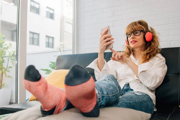 woman on the couch listening to music with headphones and mobile phone