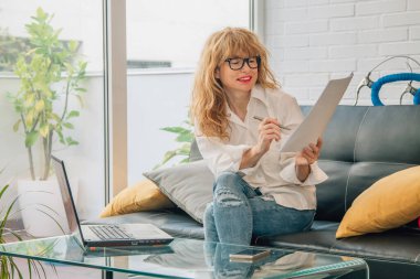 İş kadını evde bilgisayar ve belgelerle çalışıyor.