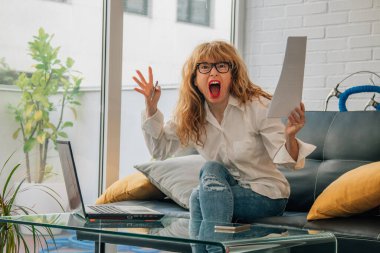 Evde bilgisayarlı kızgın bir kadın var.