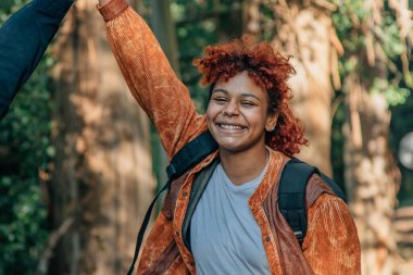 Afro-Amerikalı kadın gülümsüyor. Açık havada gezmekten hoşlanıyor.