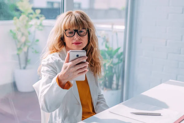 Ofis Masasındaki Kadını Cep Telefonuna Bakıyor — Stok fotoğraf