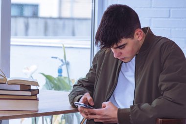 teen boy student with mobile phone at desk