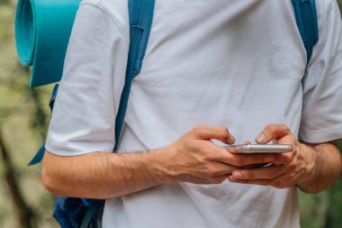 Gezintide ya da sırt çantasıyla gezintiye çıkmış cep telefonu olan genç bir adamın elleri.