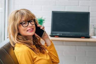 Evde ya da ofiste telefonla konuşan bir kadın.