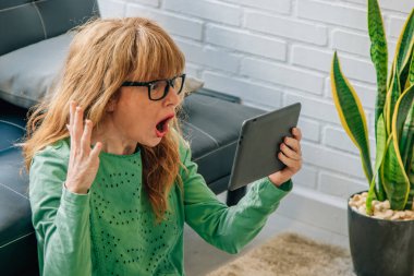 Evdeki kadın dijital tablete şaşırmış görünüyor.