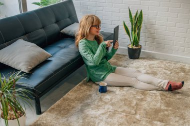 Evdeki kadın tablete bakıyor ya da internette konuşuyor. 