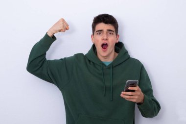 Genç bir öğrenci, beyazlar içinde izole edilmiş cep telefonuyla heyecanla bağırıyor. 