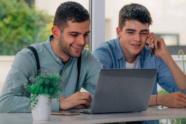 Masalarında dizüstü bilgisayarları olan gençler. 