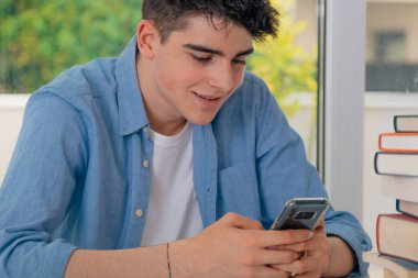 Öğrenci masasında cep telefonuyla eğleniyor