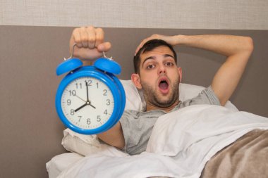 Alarmlı ya da alarmlı bir adam yatakta ve şaşırmış bir ifade