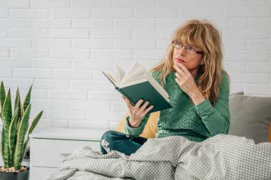 Kadın yatakta bir kitap okuma