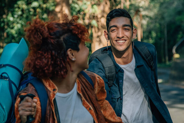 young multiethnic couple with backpacks hiking or trekking