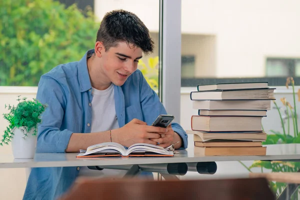 Tinédzser Fiú Tanul Mobiltelefonnal Asztalnál Könyvek — Stock Fotó