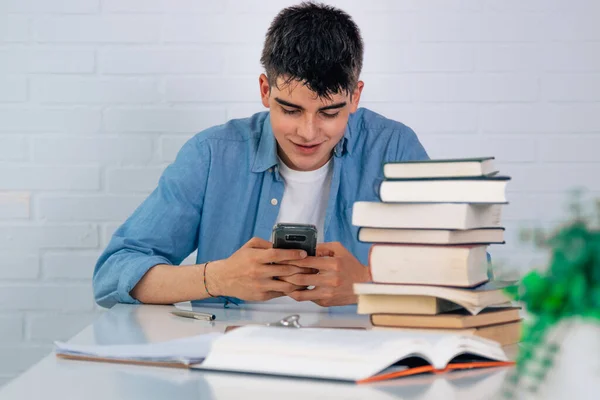 Estudiante Con Teléfono Móvil Escritorio Con Libros Apilados — Foto de Stock