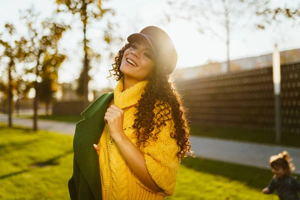 Una ragazza felice e sorridente in berretto passeggia in un parco autunnale al tramonto — Foto Stock