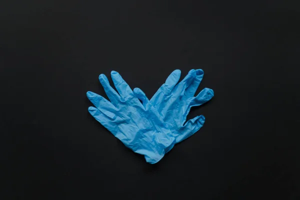 Символ сердца состоит из двух медицинских перчаток на черном фоне. День Святого Валентина во время пандемии. Символ голубя, поддержка — стоковое фото