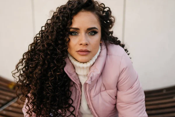 Large portrait of a girl with curls in a pink jacket on a light background — Stock Photo, Image