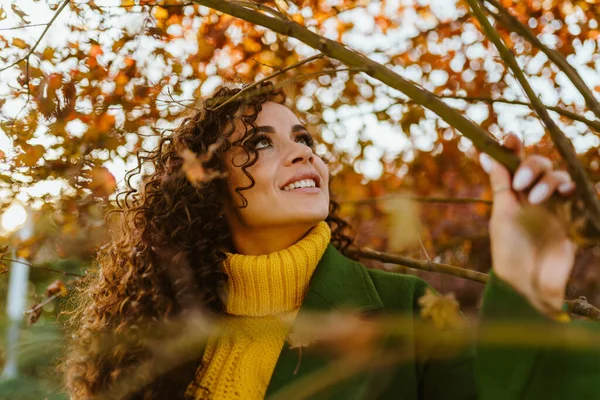 Uma menina gosta de árvores de outono no parque, olha para o lado e para cima, entre os ramos — Fotografia de Stock
