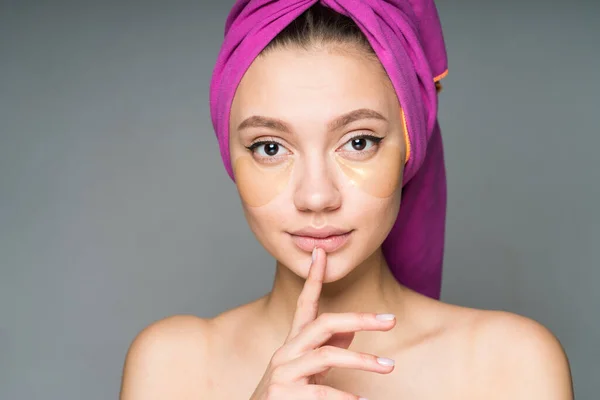 Uma menina com ombros nus e uma toalha na cabeça colocou o dedo nos lábios pedindo silêncio. close-up — Fotografia de Stock