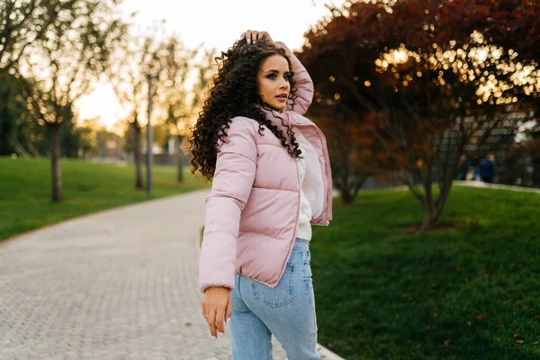 Looking over the shoulder of someone looking in the park is a beautiful girl in a warm jacket and jeans — Stock Photo, Image