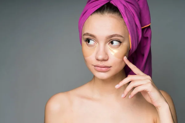 Un mannequin avec des épaules nues et une serviette enroulée autour de sa tête faisant des procédures de patch cosmétique sous les yeux — Photo