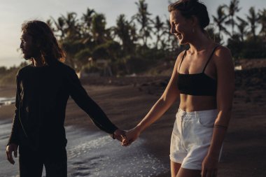 Aşık bir adam bir kadının elini tutar ve kadın okyanusta yürür.