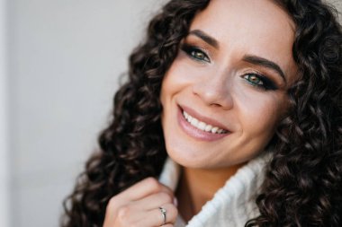 Güzel bir gülümseme, beyaz dişli ve muhteşem dumanlı, kıvırcık esmerin yeşil gözleri. yakın plan