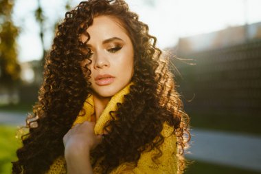 Yakın plan. Şatafatlı baştan çıkarıcı güzellik, bakışlarını harika gözlerle alçaltmış ve dudaklarını gururla açmış elleriyle boğazını kapatmış.