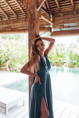 Sütunun üzerinde güzel bir poz uzun bir elbise içinde güzel bir kız duruyor.