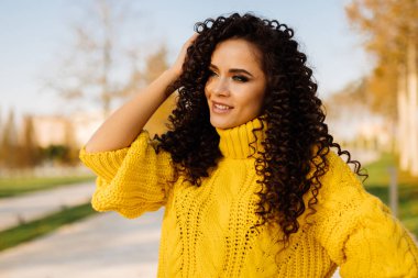 Sonbahar parkında siyah bukleleriyle alay eden bir kızın yüzündeki şaşkın gülümseme. yakın plan