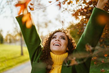 Güzellik zaferle ellerini gökyüzüne attı ve sonbahar parkında gülümsedi.